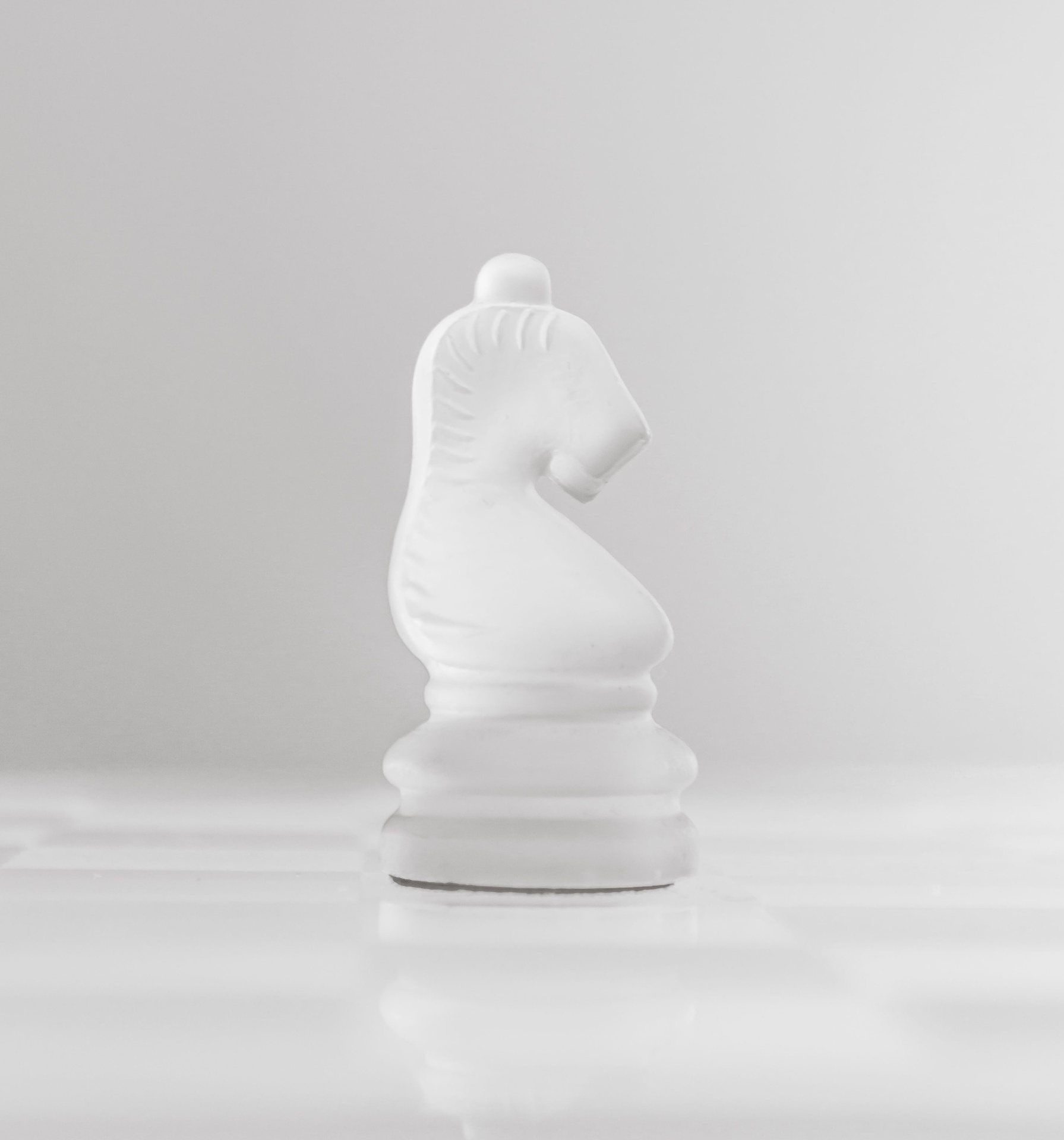 White knight chess piece on a reflective surface